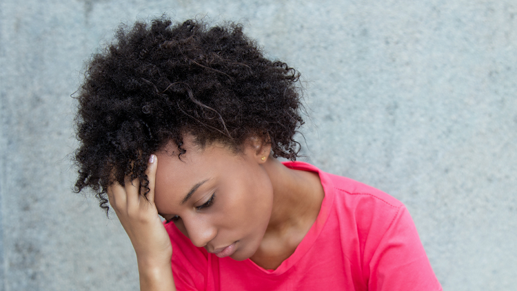 Photograph of a depressed woman in a pink shirt, with her head in her hands