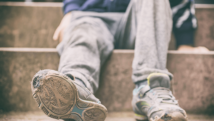 young child with worn out sneakers