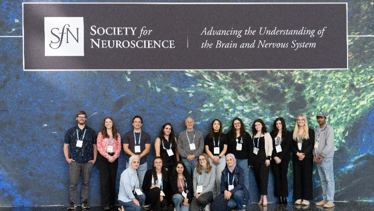 Attendees posing in front of a large SfN sign