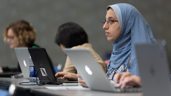 Three Annual Meeting attendees sitting at a desk with their laptop computers