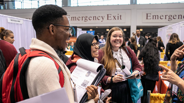 Three Neuroscience 2019 attendees conversing at the Graduate School Fair